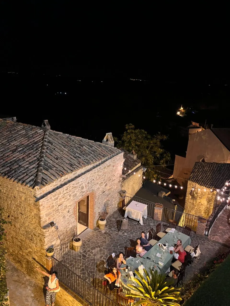 Cena nocturna en una terraza de piedra en Tursi, nomadas digitales compartiendo una comida al aire libre