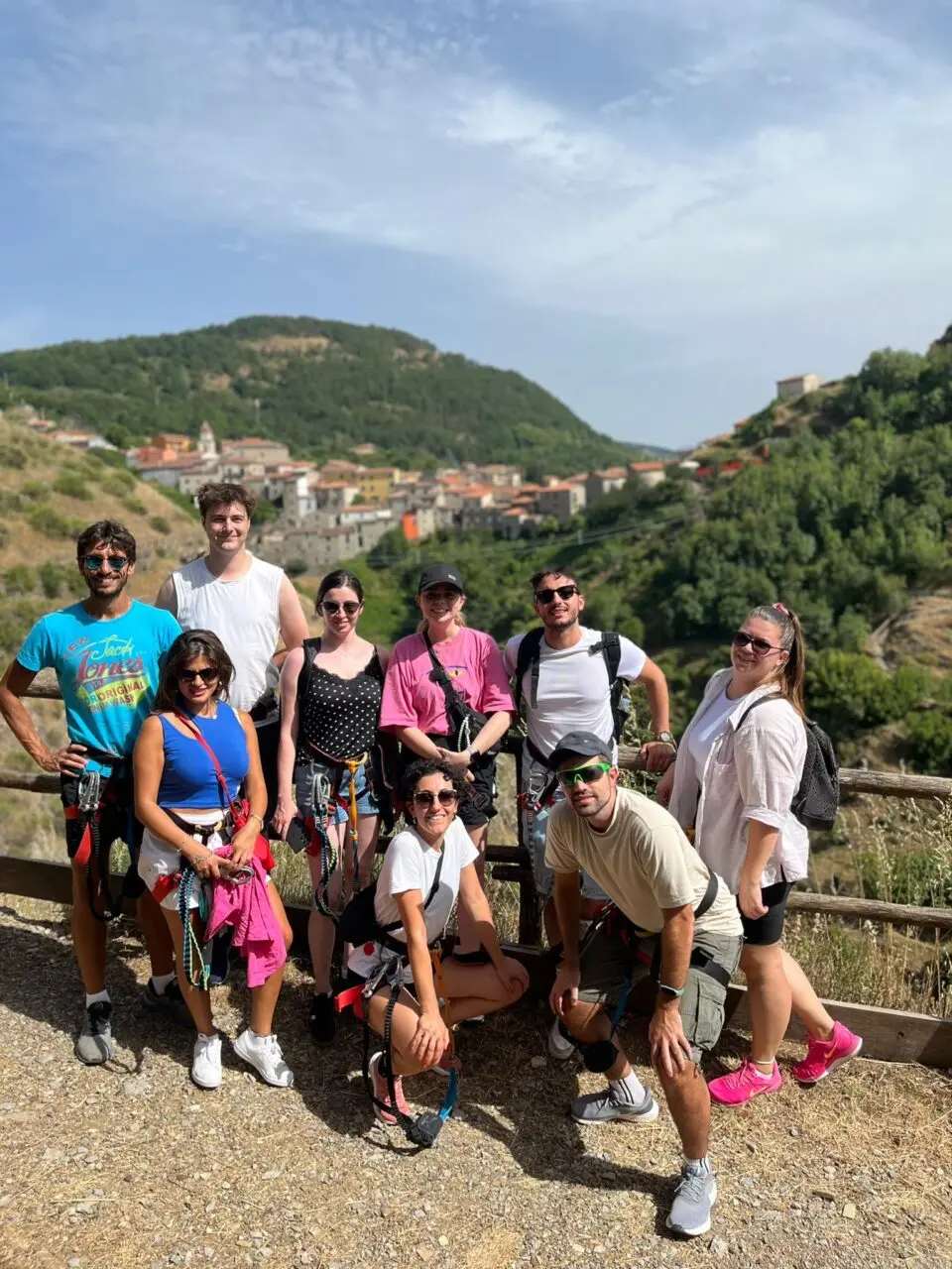 Group photo of hikers with harnesses in front of a hillside village