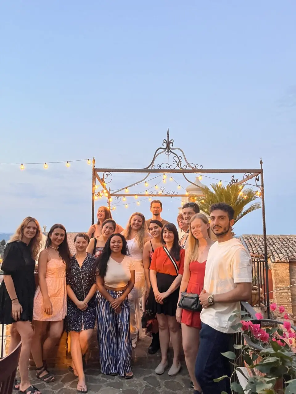Group photo at sunset on a rooftop terrace with string lights