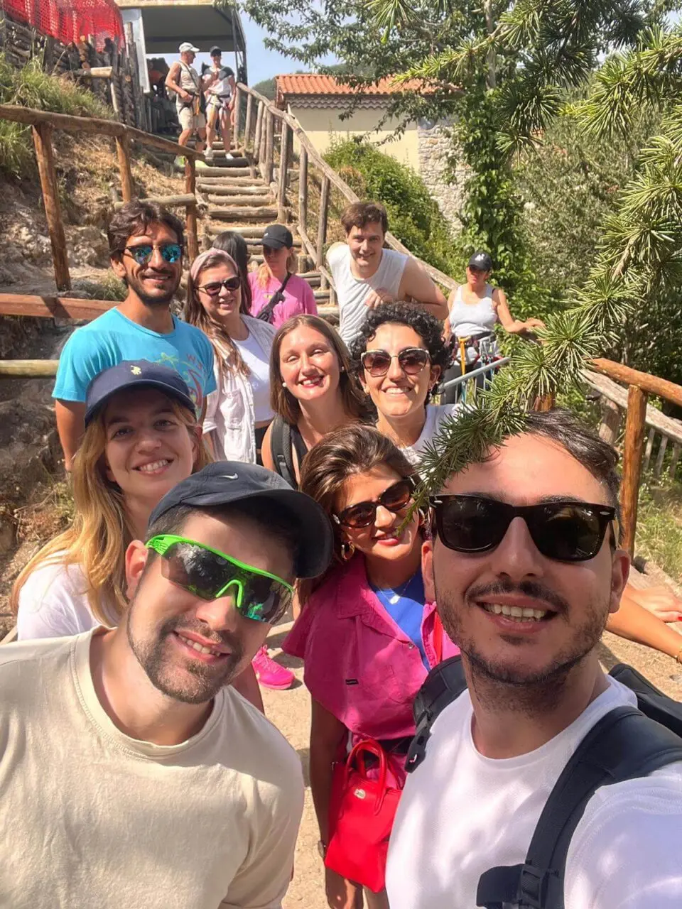Grupo de nomadas digitales sonriendo en una escalera de madera durante una excursion al aire libre en Tursi